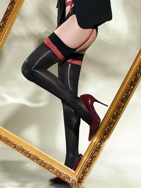 A woman posing in a black glossy thigh high stockings with red lace details, and attached red garter straps.