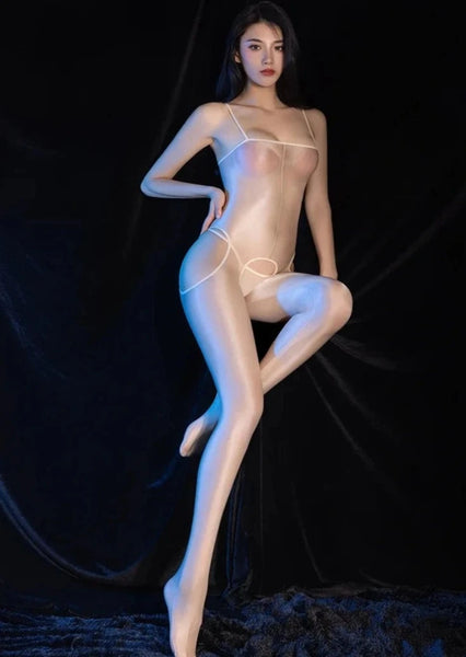 A woman posing in a beige glossy sheer suspender bodystocking with spaghetti straps, and an open crotch.