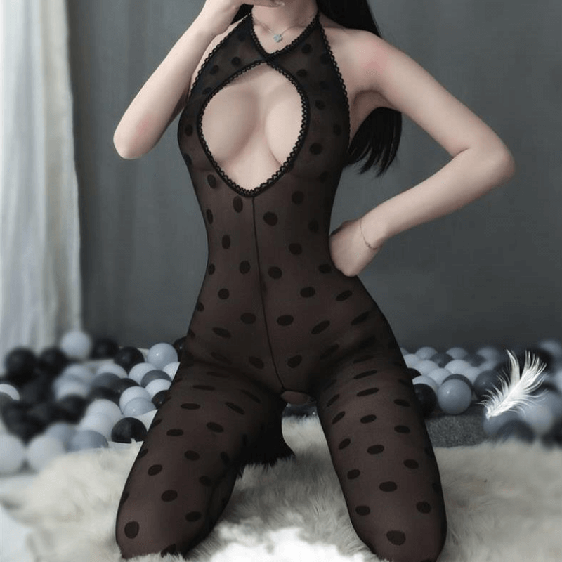 Front view of lady wearing black sheer polka dot bodystocking featuring a halter neckline, a keyhole bodice, a low cut back, and an open crotch. 
